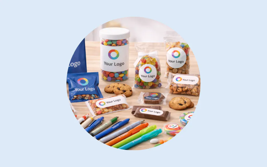 Branded promotional snacks candies pens and a mug featuring a colorful circular logo
