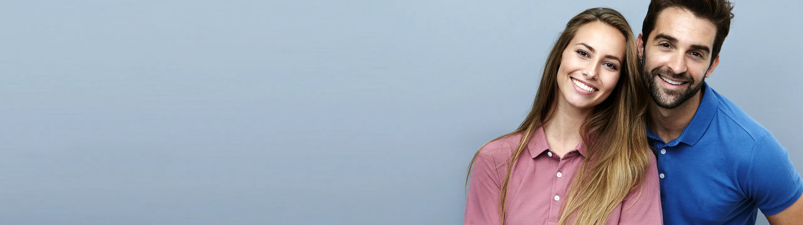 A man in a blue uniform and cap stands with crossed arms in a car workshop
