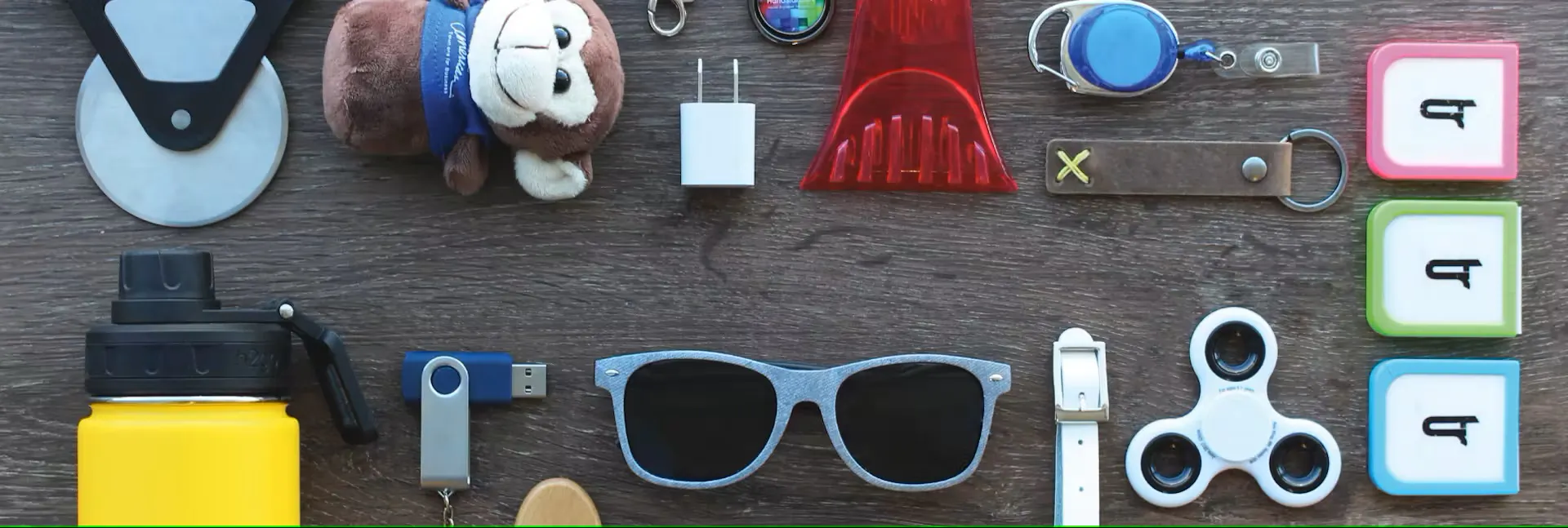 sunglasses, usb drive, water bottle, and other promo products on table