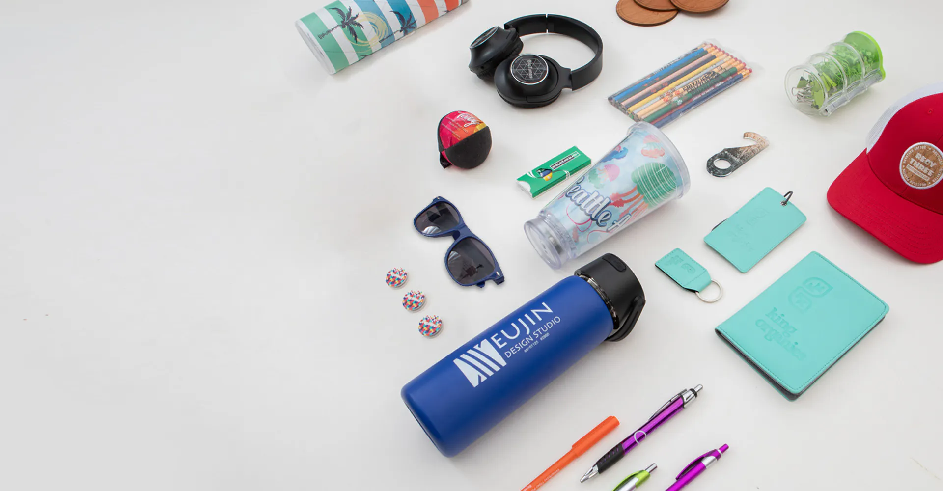 custom tumbler, notebook, pens, sunglasses, hat and other items on table