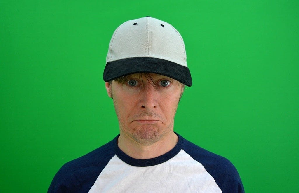 A man sitting down wearing a black ball cap