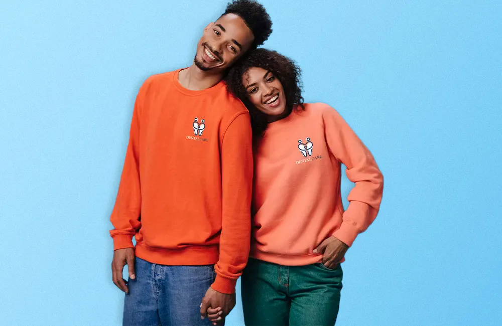 Two people wearing red and coral sweatshirts on a blue background 