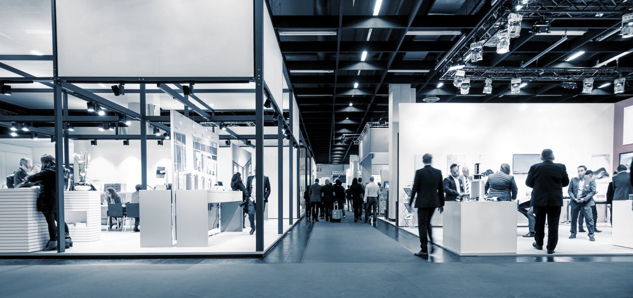 Business people walking through a trade show expo hall with booths