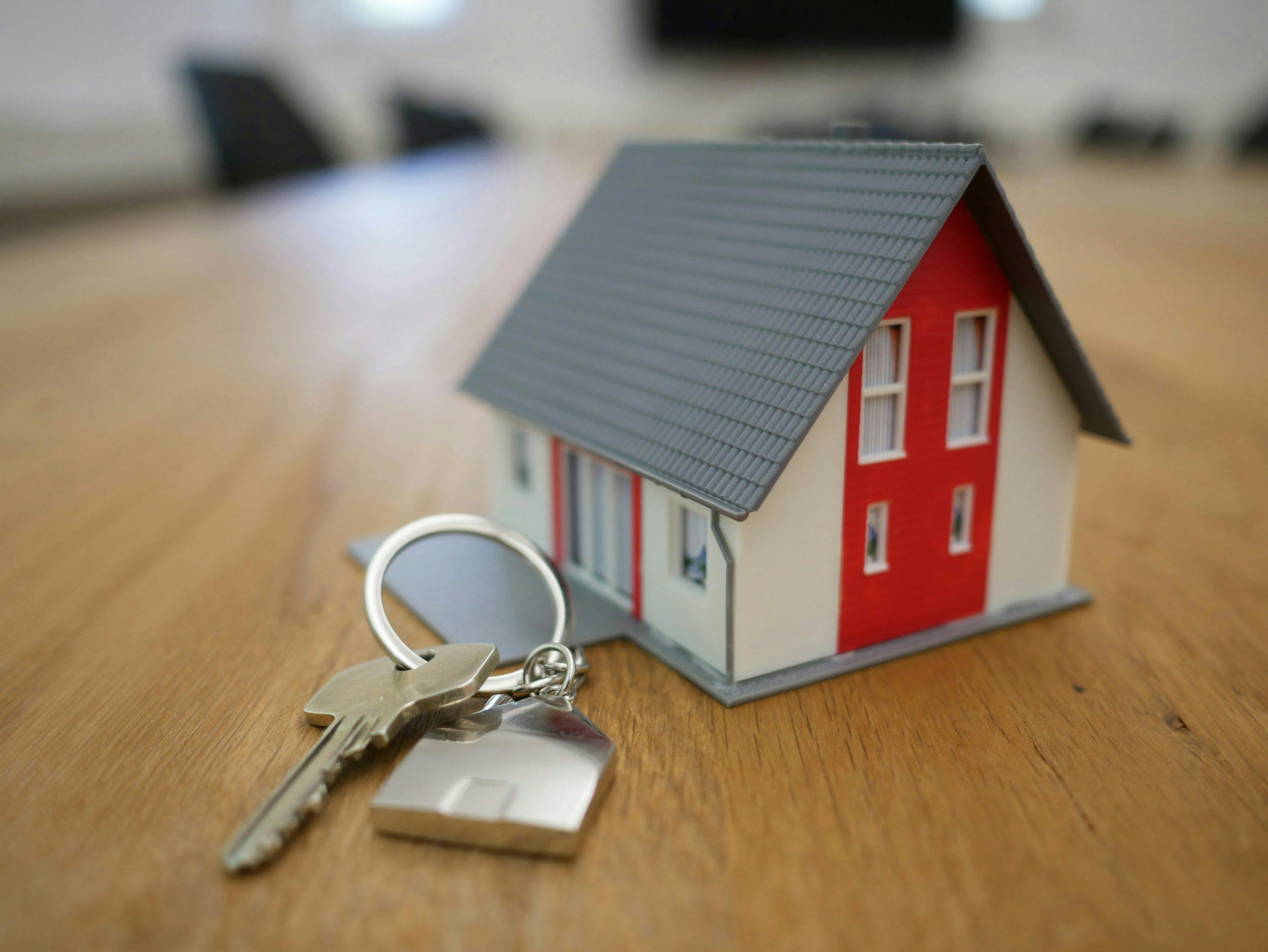 A mini house on a table next to a set of house keys