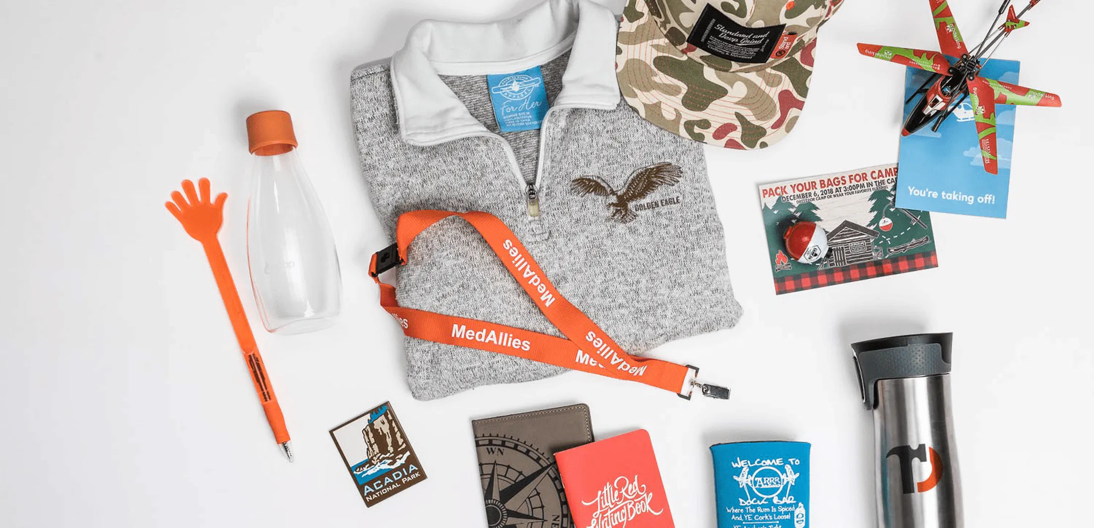 Custom promotional products including branded apparel, drinkware, notebooks, lanyards, hats, and novelty items.