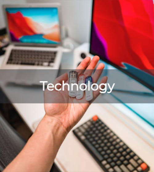 person holding flashdrives over a desk with computer accessories on it