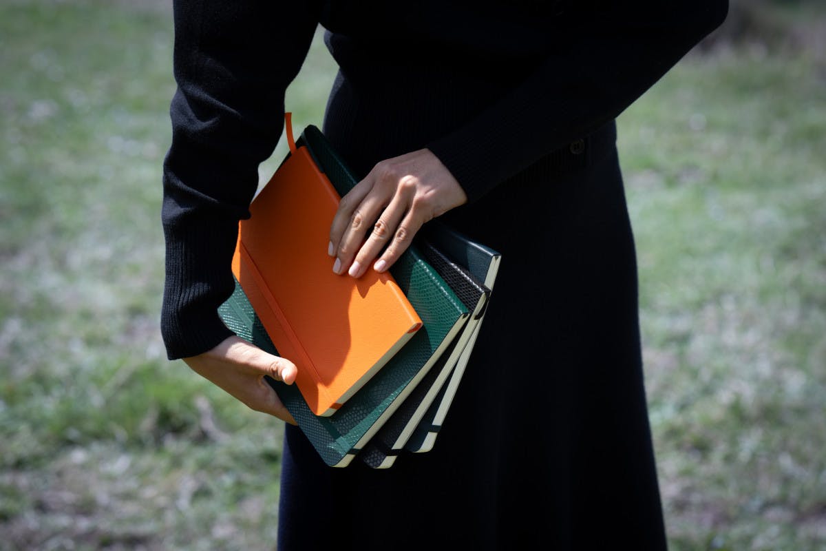 woman holding group of Moleskine journals