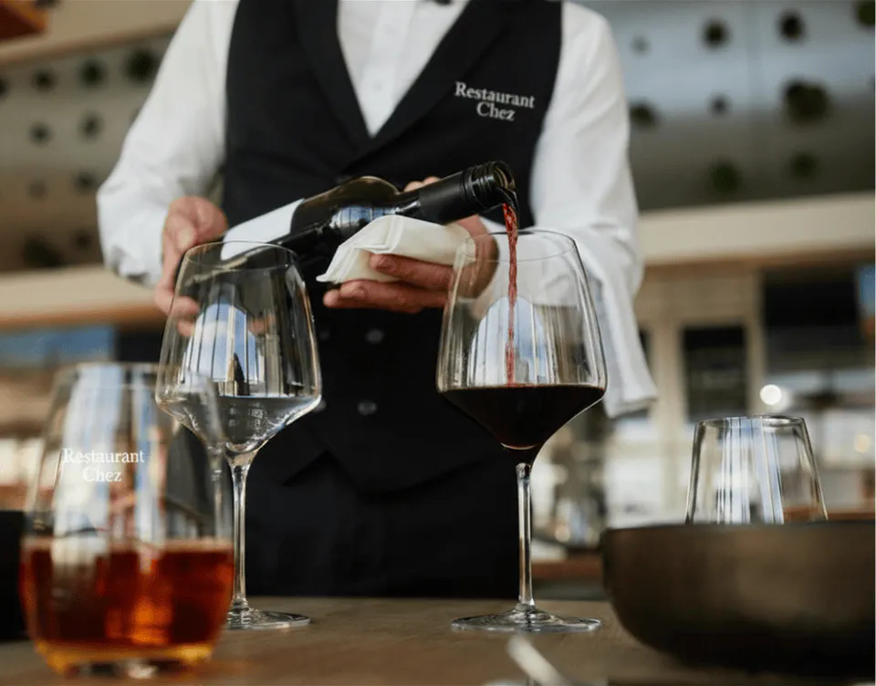 blurred tabletop with server pouring wine in the background