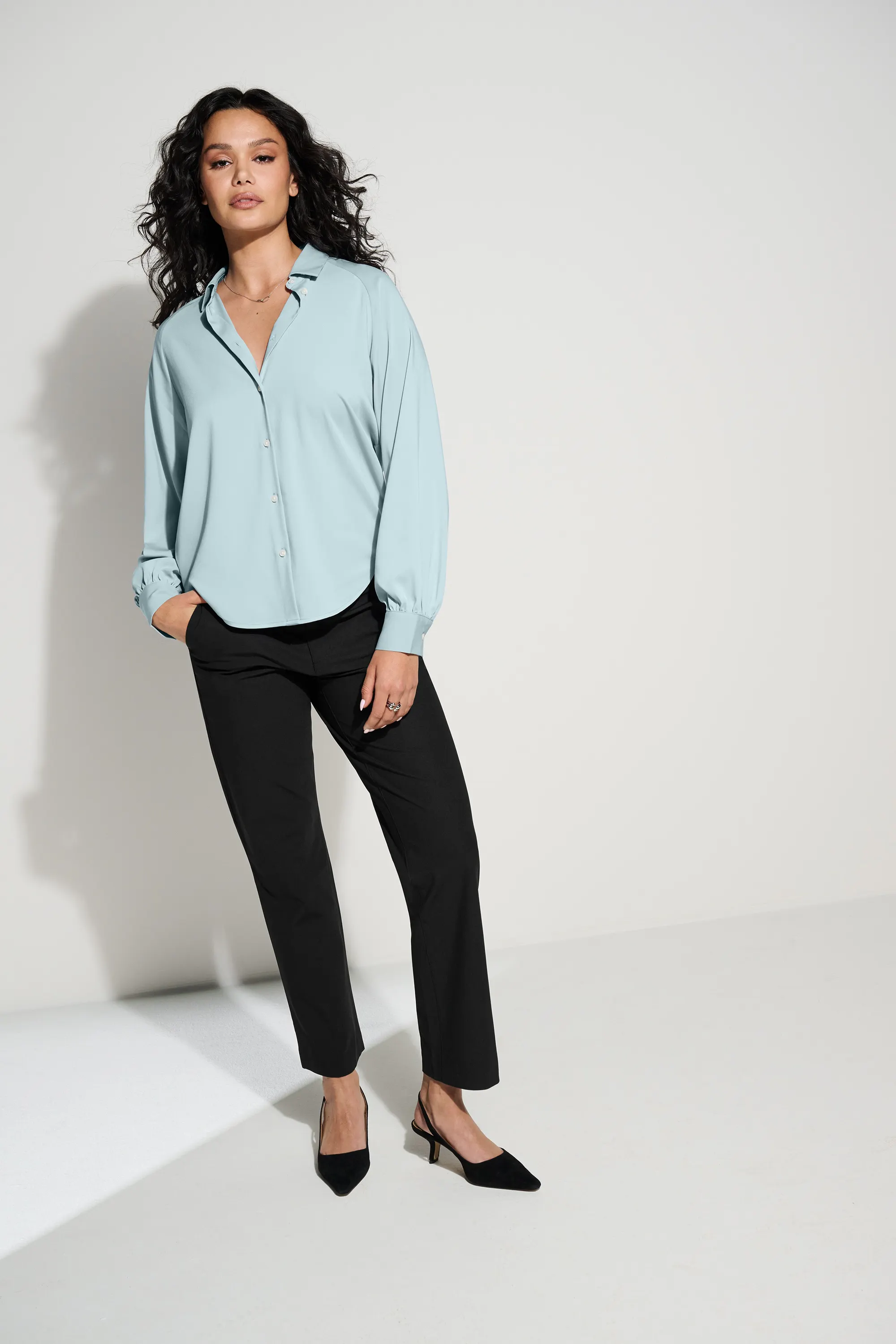 A woman wearing a crisp button down blouse and slacks stands ready for work