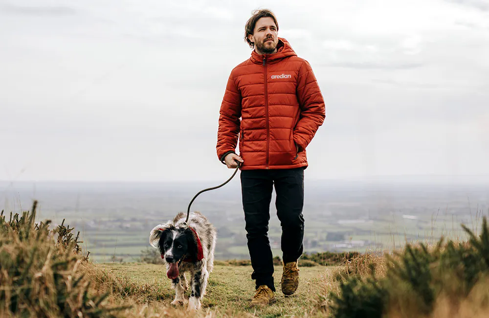 man wearing jacket walking dog